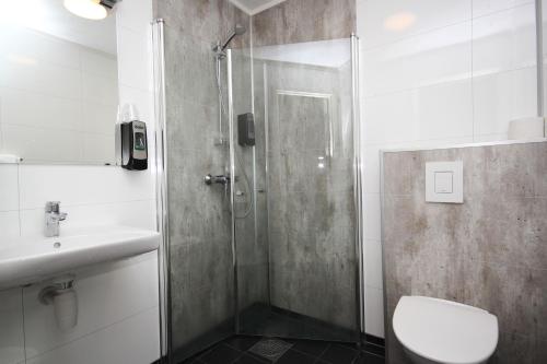 a bathroom with a shower and a toilet and a sink at Napoli Resturant & Hotell AS in Sandnessjøen