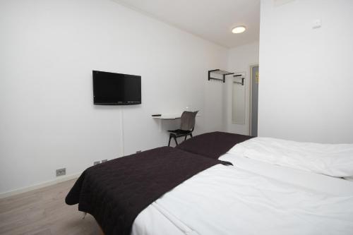 a bedroom with a bed and a desk with a tv on the wall at Napoli Resturant & Hotell AS in Sandnessjøen