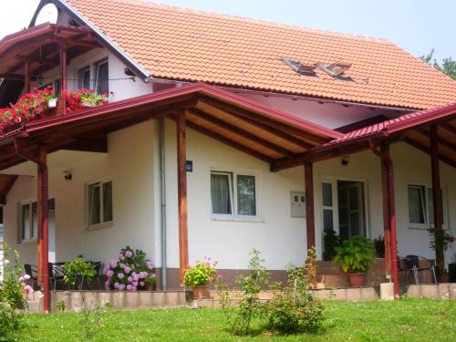 Una casa con techo rojo y flores. en Guesthouse Abrlic, en Selište Drežničko