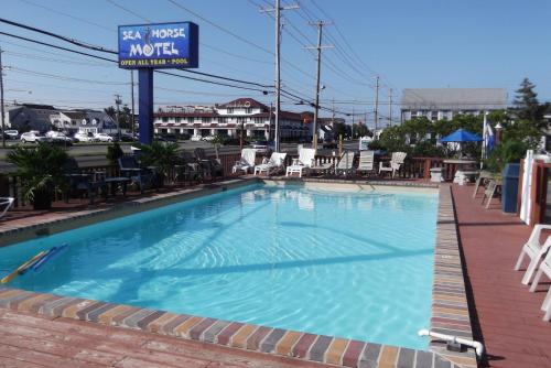 a large swimming pool with chairs and a hotel sign at Sea Horse Motel in Brant Beach