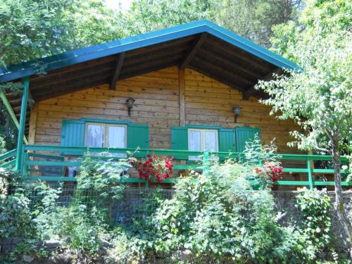 a log cabin with green windows and flowers in front at CHALET ETNA MILO in Milo