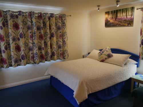 a bedroom with a bed and a curtain at Little Bullocks Farm in Takeley