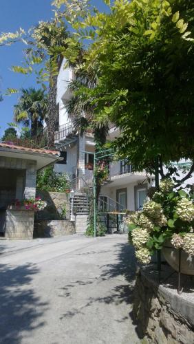 a large white house with a tree in front of it at Rooms Vukušić in Rab