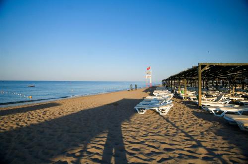 a beach with a row of white chairs and a pier at Marvida Family Eco - Ultra All Inclusive & Kids Concept in Side