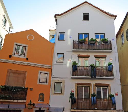 ein weißes Gebäude mit Balkonen und Topfpflanzen in der Unterkunft Casas de Fado in Lissabon