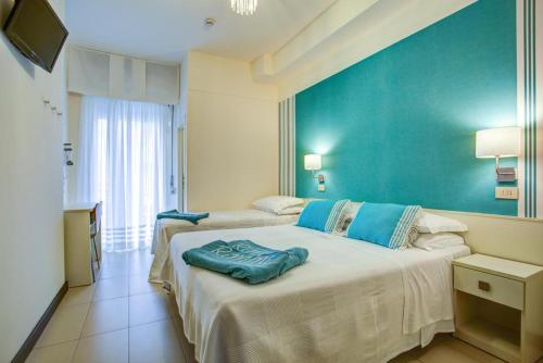 una camera con due letti e una parete blu di Hotel Konrad a Rimini