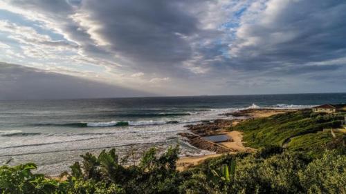a view of the beach with a rainbow in the sky at Summer Place Umzumbe in Umzumbe