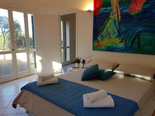 a bedroom with a large bed with a painting on the wall at Villino I Sugheri in Marciana Marina