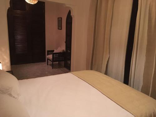 a bedroom with a bed and a chair and a window at Dar 23 in Tangier