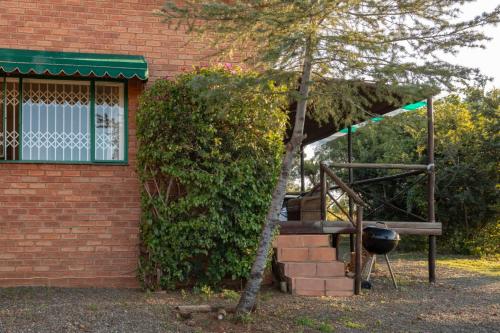 a grill next to a brick building with a tree at Olive Tree Farm in Magaliesburg