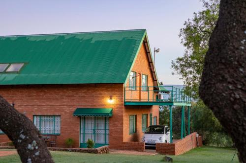 a red brick house with a green roof at Olive Tree Farm in Magaliesburg