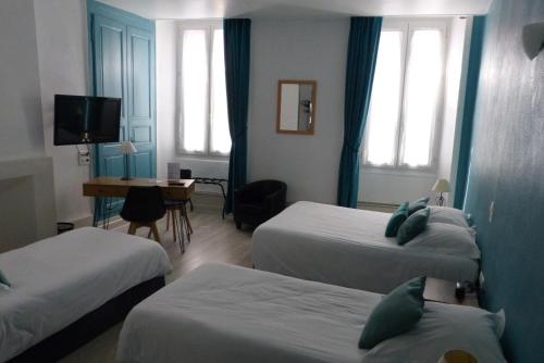 a hotel room with three beds and a desk at Hotel des Alpes in Die