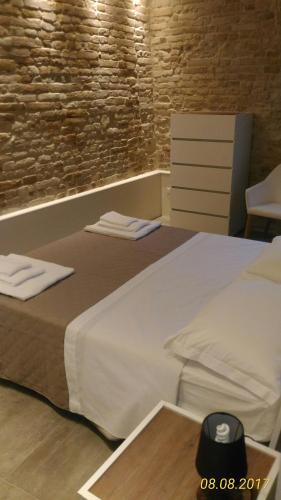 a bedroom with a white bed with a brick wall at B&B Dimora Damiani in Montefiore dellʼAso