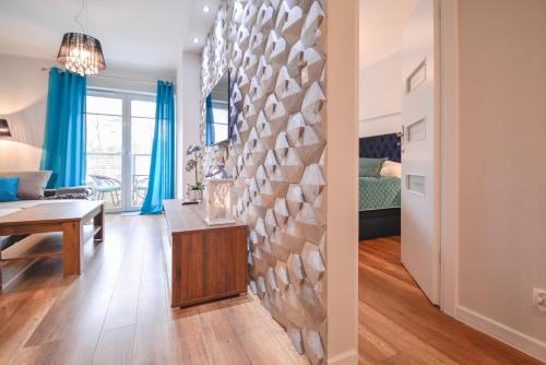 una sala de estar con mesa y una habitación con cortinas azules en Osiedle Cesarskie Apartamenty - Parking - Apartamenty Bryza, en Świnoujście