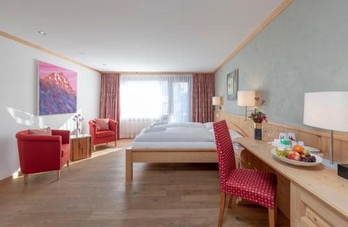 a bedroom with a bed and a table and chairs at Hotel Alpina in Klosters