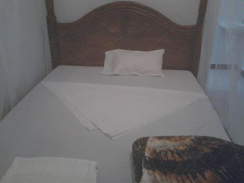 uma cama branca com uma cabeceira em madeira e uma almofada em FREEDOM Guest House em Wakiso