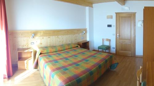 a bedroom with a bed with a colorful comforter at Albergo Ristorante Baraglia in Mello