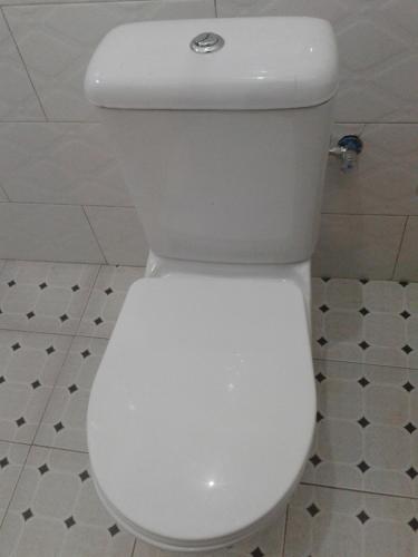 a white toilet with the lid down in a bathroom at FREEDOM Guest House in Wakiso