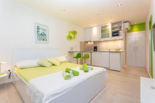 a white bedroom with a large bed and a kitchen at Apartments Nona 1 in Hvar