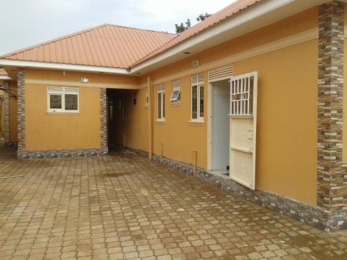 a small yellow house with a brick driveway at FREEDOM Guest House in Wakiso