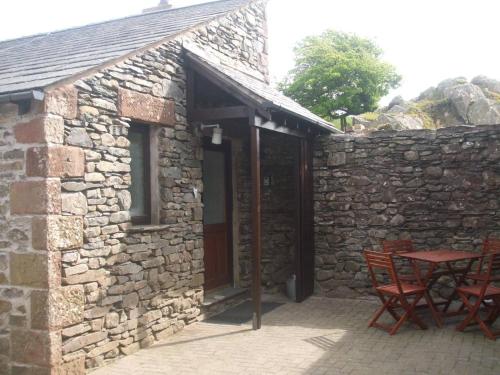 a stone building with two chairs and a table at Tethera at Coal Yeat in Spark Bridge