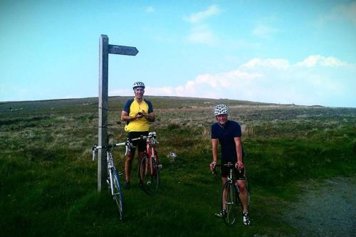 two men are standing next to their bikes in a field at Tethera at Coal Yeat in Spark Bridge