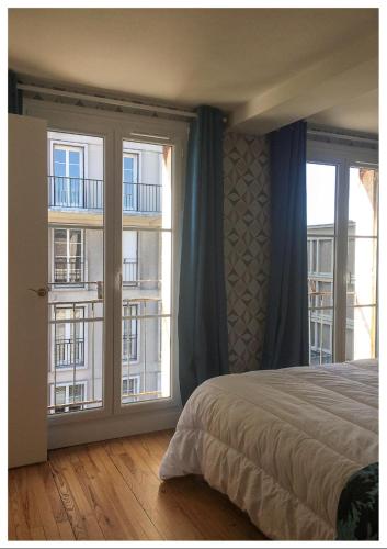a bedroom with a bed and two large windows at Appartement Perret avec vue mer en centre ville in Le Havre