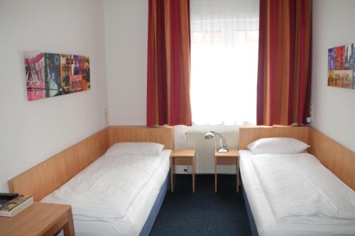 a room with two beds and a table and a window at Hotel Römerhof Hanau by Trip Inn in Hanau am Main