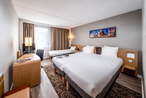 een hotelkamer met een groot bed en een bureau bij Novotel Breda in Breda