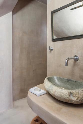 a bathroom with a stone sink and a mirror at Luxury Villa Artemis by Mykonos Luxury in Elia Beach