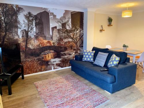 a living room with a blue couch and a wall mural at Cosy Corner House in Kettering