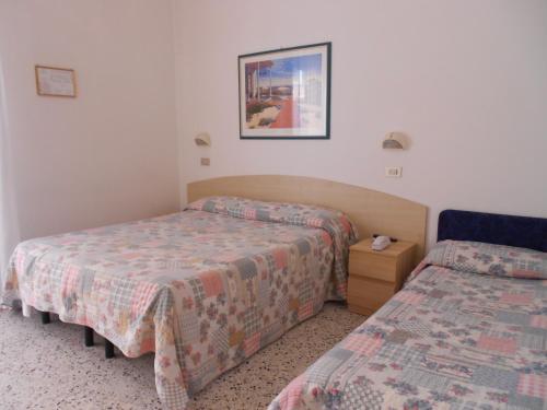 a hotel room with two beds and a night stand at Hotel Laguna Blu in Rimini