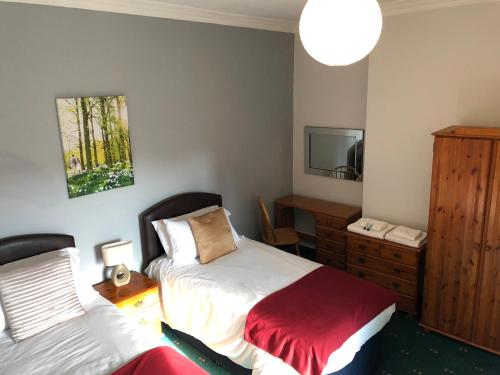 a bedroom with two beds and a dresser and a mirror at The Clee Hotel - Cleethorpes, Grimsby, Lincolnshire in Cleethorpes