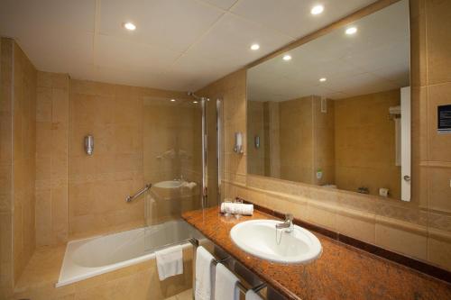 uma casa de banho com um lavatório, uma banheira e um espelho. em Grupotel Alcudia Pins em Playa de Muro