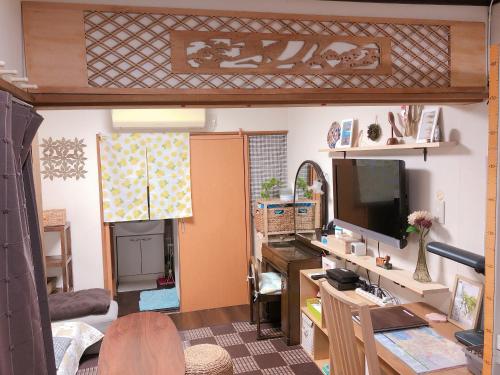 a living room with a tv and a desk with a computer at Ryokoheya Tenchokan in Osaka