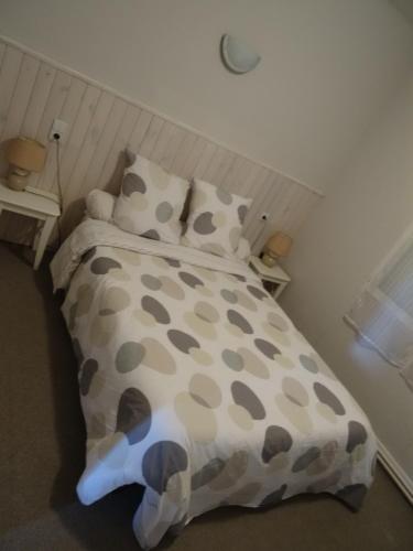 uma cama com um edredão e almofadas castanhos e brancos em Au Bon Accueil em Alban