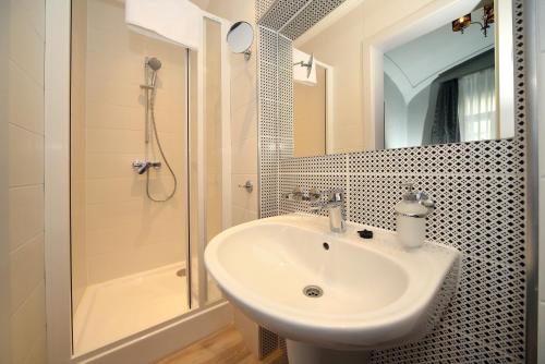 a bathroom with a sink and a shower and a mirror at Várkapu Panzió in Eger