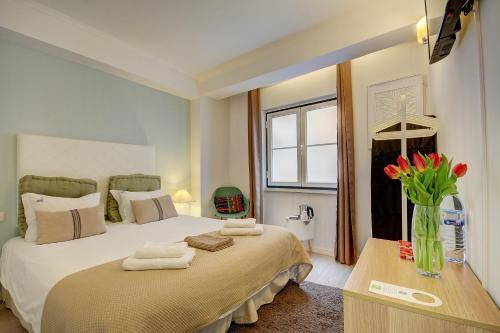um quarto com uma cama grande e um vaso de flores em Inn Bairro Alto BA Sweet em Lisboa