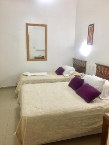 two beds in a room with a mirror on the wall at Hotel Plaza San Juan in San Juan
