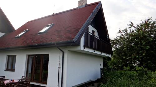 a white house with a red roof and a balcony at Prázdninový dům - PACL Červená Řečice in Červená Řečice