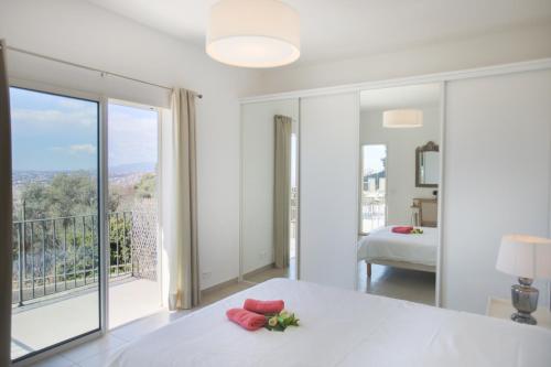 biała sypialnia z łóżkiem i dużym oknem w obiekcie Vinaigrier Hills VI3086 by Riviera Holiday Homes w Nicei