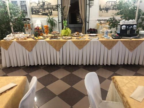 una mesa con comida y sillas blancas en Antico Hotel Moderno en Piombino