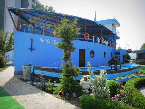 a blue boat in a garden with a tree at Hotel Hercules Jupiter in Jupiter