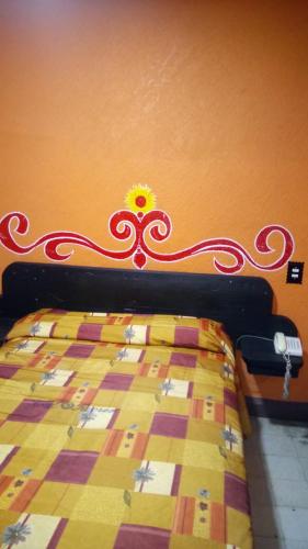 un letto con una trapunta rossa e gialla appesa a un muro di Hotel Recreo a Città del Messico