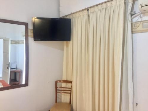 Habitación con cortina y TV en la pared. en Hotel Plaza San Juan en San Juan