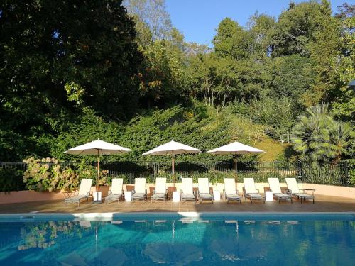 a group of chairs and umbrellas next to a swimming pool at Hôtel Chantaco Golf & Wellness in Saint-Jean-de-Luz