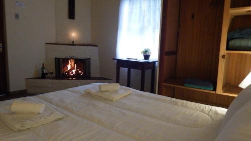 a bedroom with a white bed and a fireplace at Hotel Refazenda in Visconde De Maua