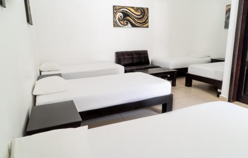 a room with three beds and a chair at We playa Hotel in Playa del Carmen