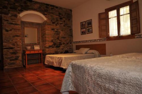 - une chambre avec 2 lits et un mur en pierre dans l'établissement Casa Rural "Casa Isla del Zújar", à Castuera