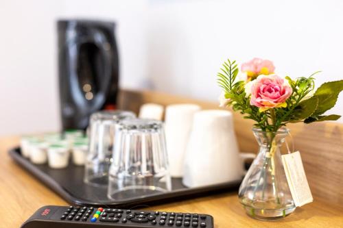 a remote control and a vase of flowers on a table at Wellesley Hotel in Ilford